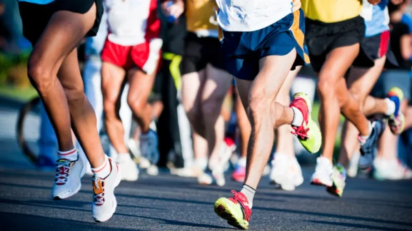 Κοντινό πλάνο στα πόδια δρομέων που τρέχουν σε αγώνα δρόμου - Το πλήρες ημερολόγιο για αγώνες τρεξίματος, μαραθώνιους και trail στην Ελλάδα το 2026 από το Gymscouter.