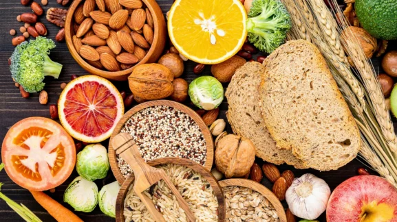 Ποικιλία υγιεινών τροφών όπως αμύγδαλα, κινόα, φρούτα και λαχανικά σε ξύλινο φόντο - 10 Μύθοι διατροφής που σου κλέβουν τα αποτελέσματα από το Gymscouter.